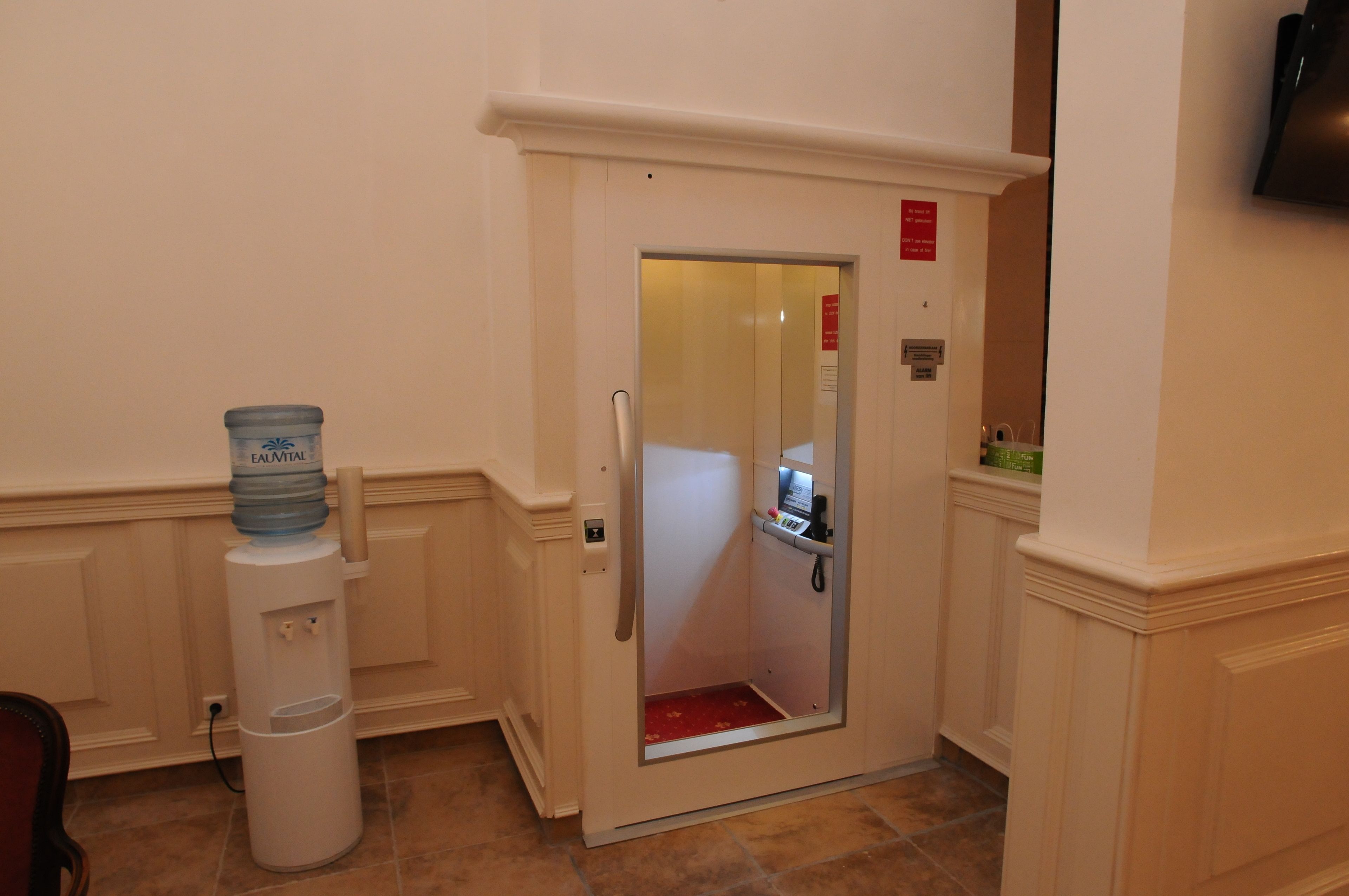A hotel elevator with a water dispenser and a control panel.