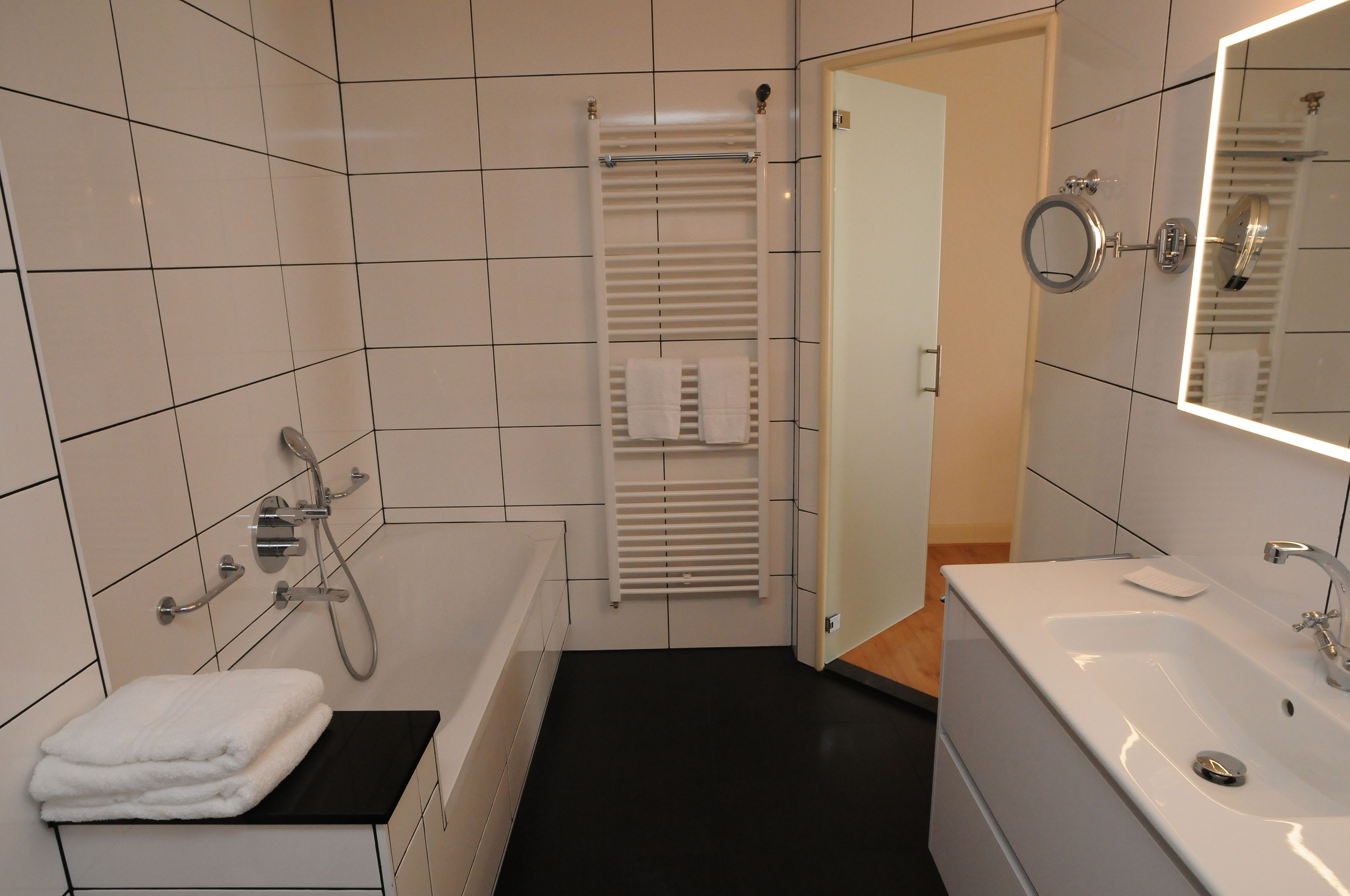 Ein modernes Badezimmer mit einer Badewanne, einem Waschbecken und einem Spiegel.
