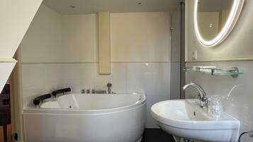 A modern bathroom with a freestanding bathtub, a sink, and a glass shower enclosure.