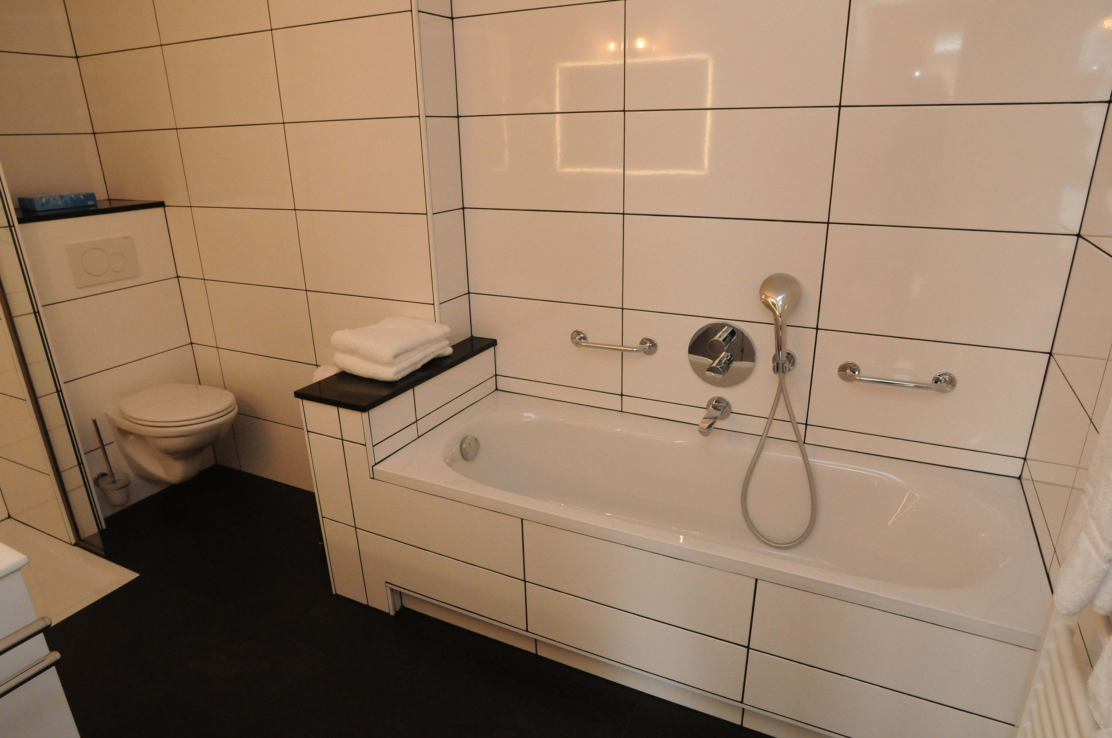 Un bagno moderno con una vasca da bagno bianca, un water e un lavandino.