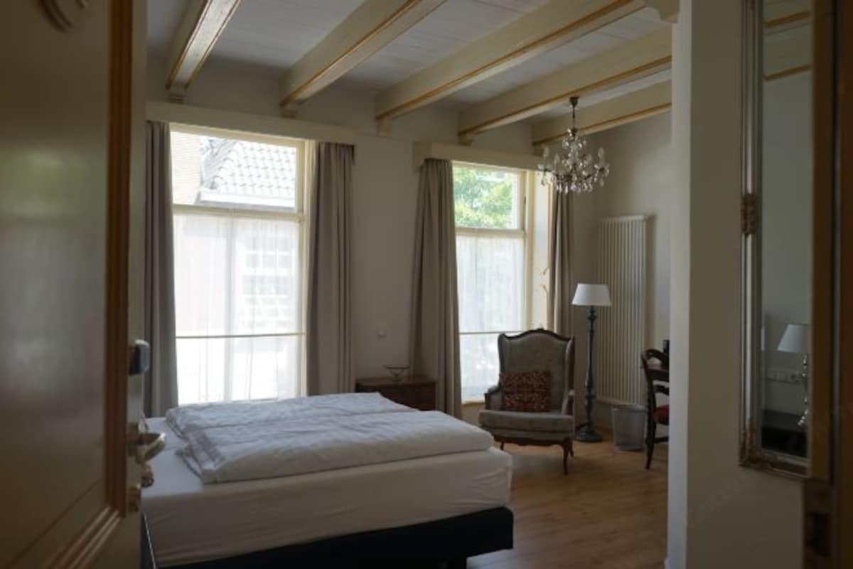 Un dormitorio con una cama, una silla, una lámpara y un candelabro.