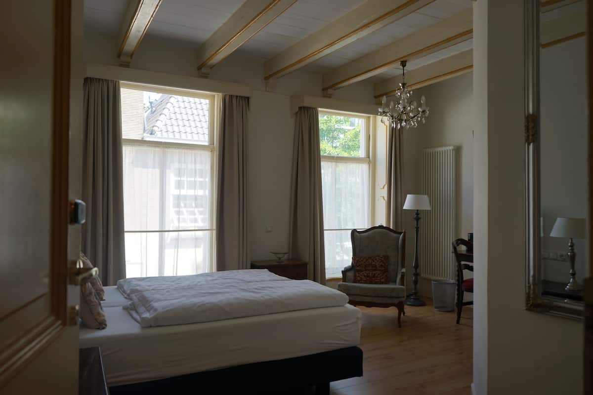 Un dormitorio con una cama grande, una silla, una lámpara y un candelabro.
