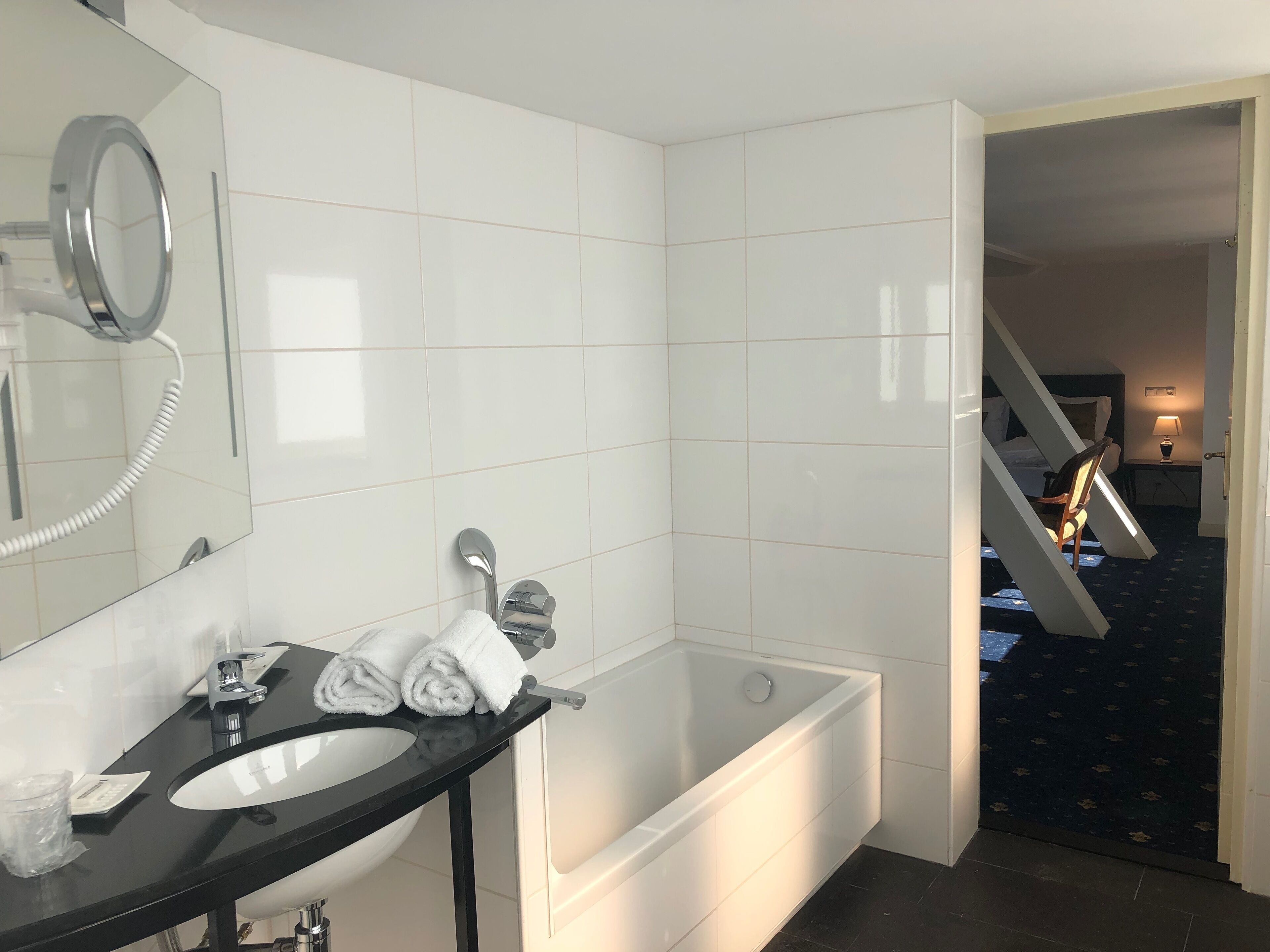 A modern bathroom with a black vanity, white sink, and a large bathtub.