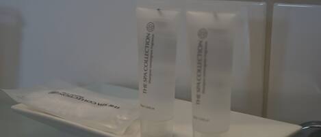 Un baño con un lavamanos blanco y dos botellas blancas que dicen "The Spa Collection" sobre una repisa blanca.
