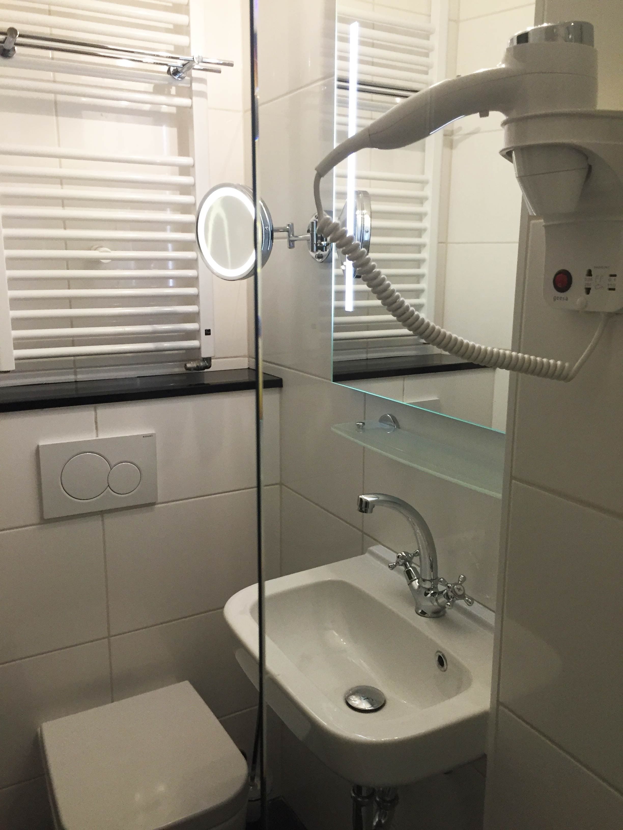 A bathroom with a white sink, a mirror, and a handheld showerhead.