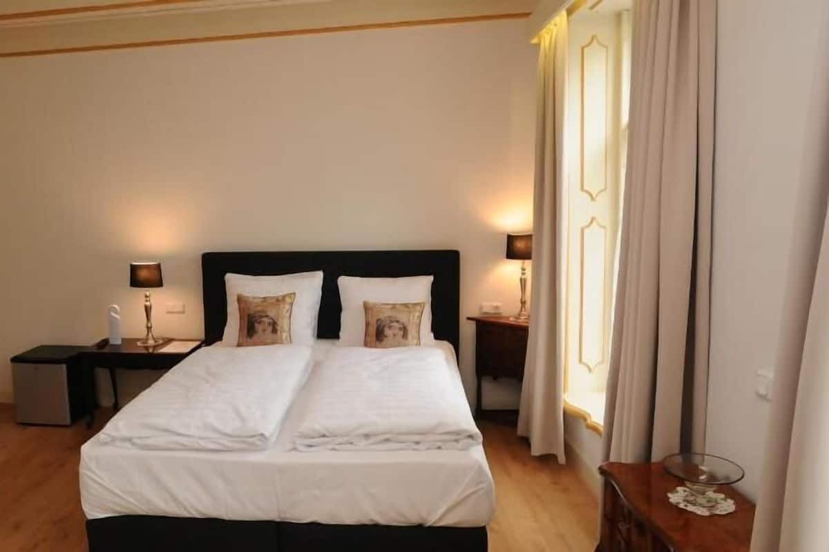 Habitación de hotel con cama, dos mesitas de noche y una ventana con cortinas.