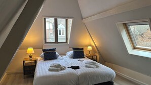 Een slaapkamer met een groot bed, twee nachtkastjes met lampen, een raam en een dakraam.