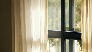 A hotel room with a bed, a window with curtains, and a view of the outside balcony. - The Corner House (Seville)