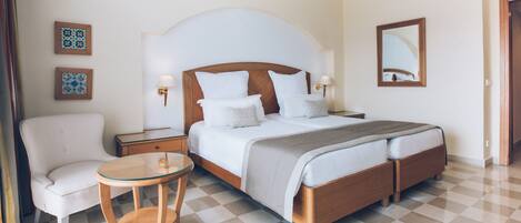 Una habitación de hotel con una cama grande, una silla, una mesita pequeña y una mesita de noche.