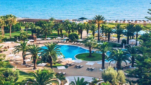 Un resort con una piscina grande, palmeras y vistas al océano.