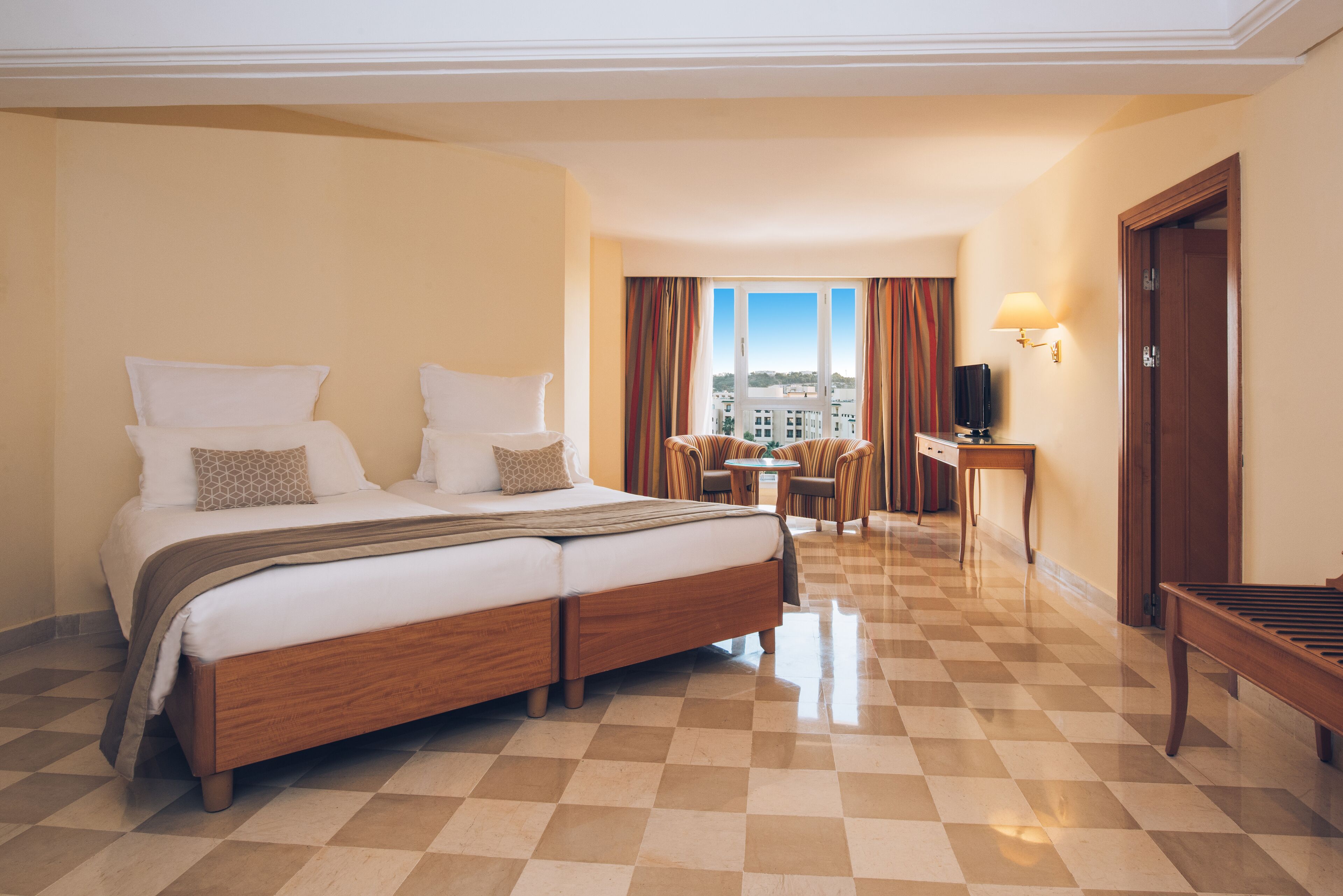 Habitación de hotel con una cama grande, un escritorio, una silla y vistas de la ciudad.