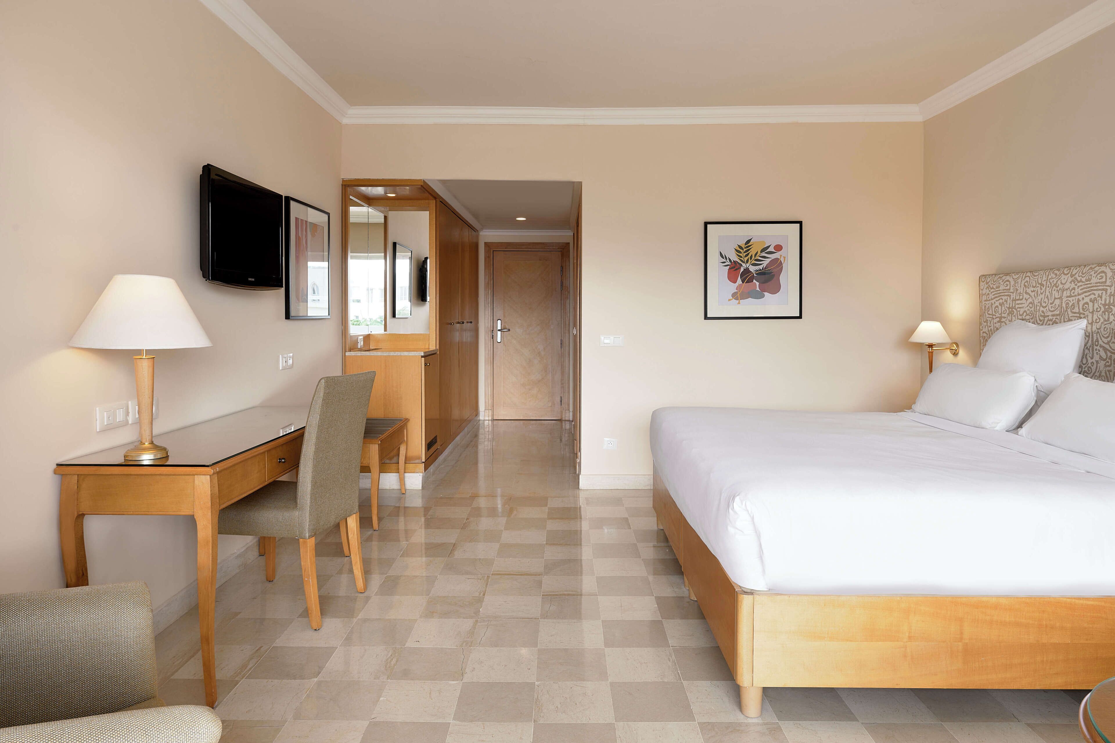 Une chambre d’hôtel équipée d’un lit, d’un bureau, d’une chaise et d’un téléviseur.