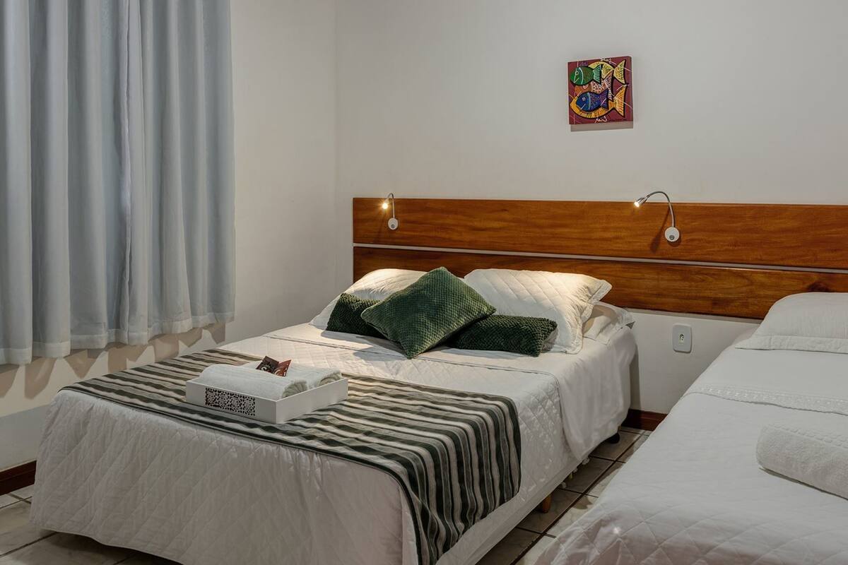 A hotel room with a wooden headboard, a bed with striped bedding, a green pillow, and a small table with a tray.