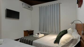 Een slaapkamer met een bed, nachtkastje en een aan de muur bevestigde televisie.