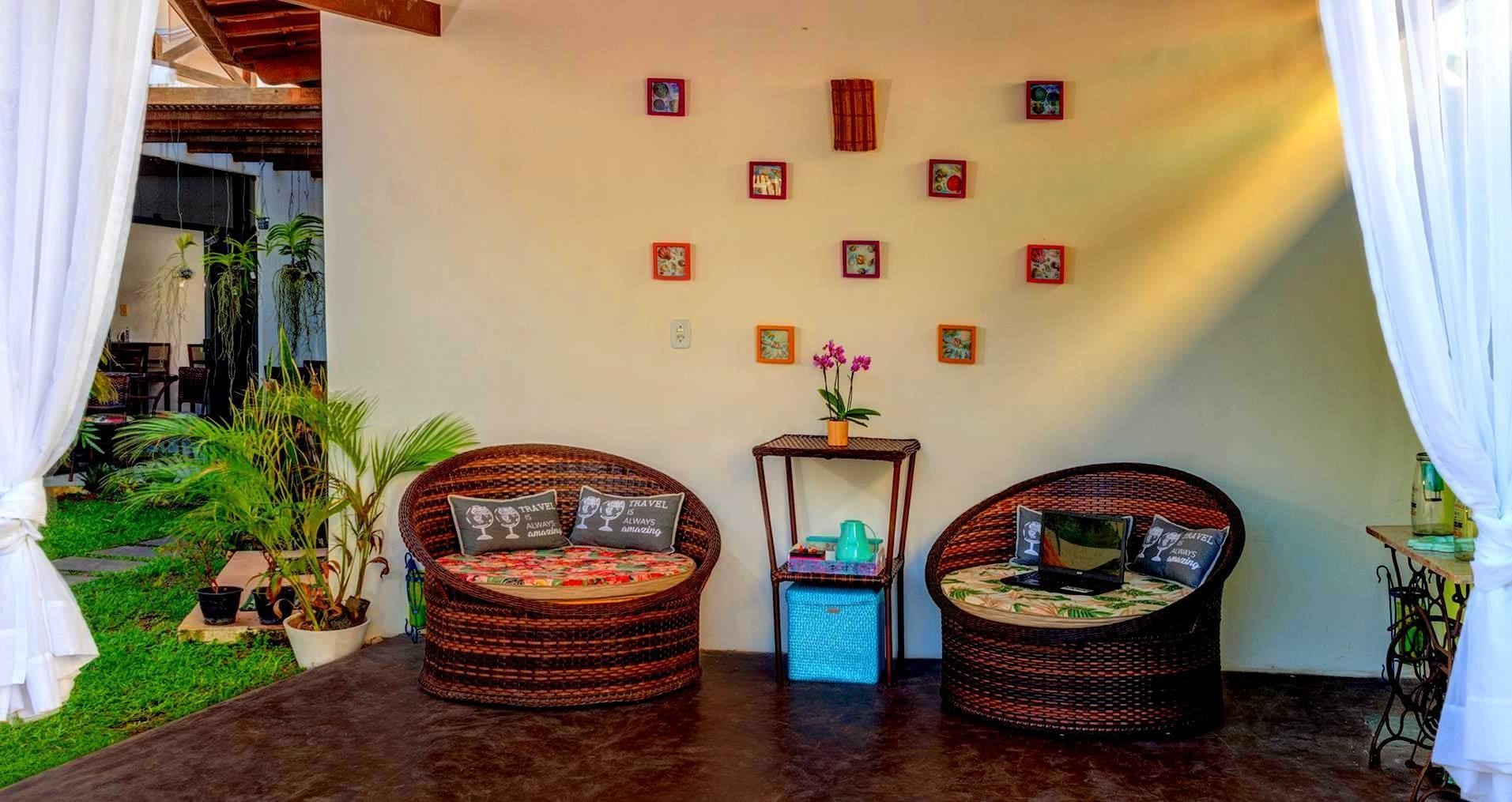 A cozy room with two wicker chairs, a small table, and a wall decorated with framed pictures.