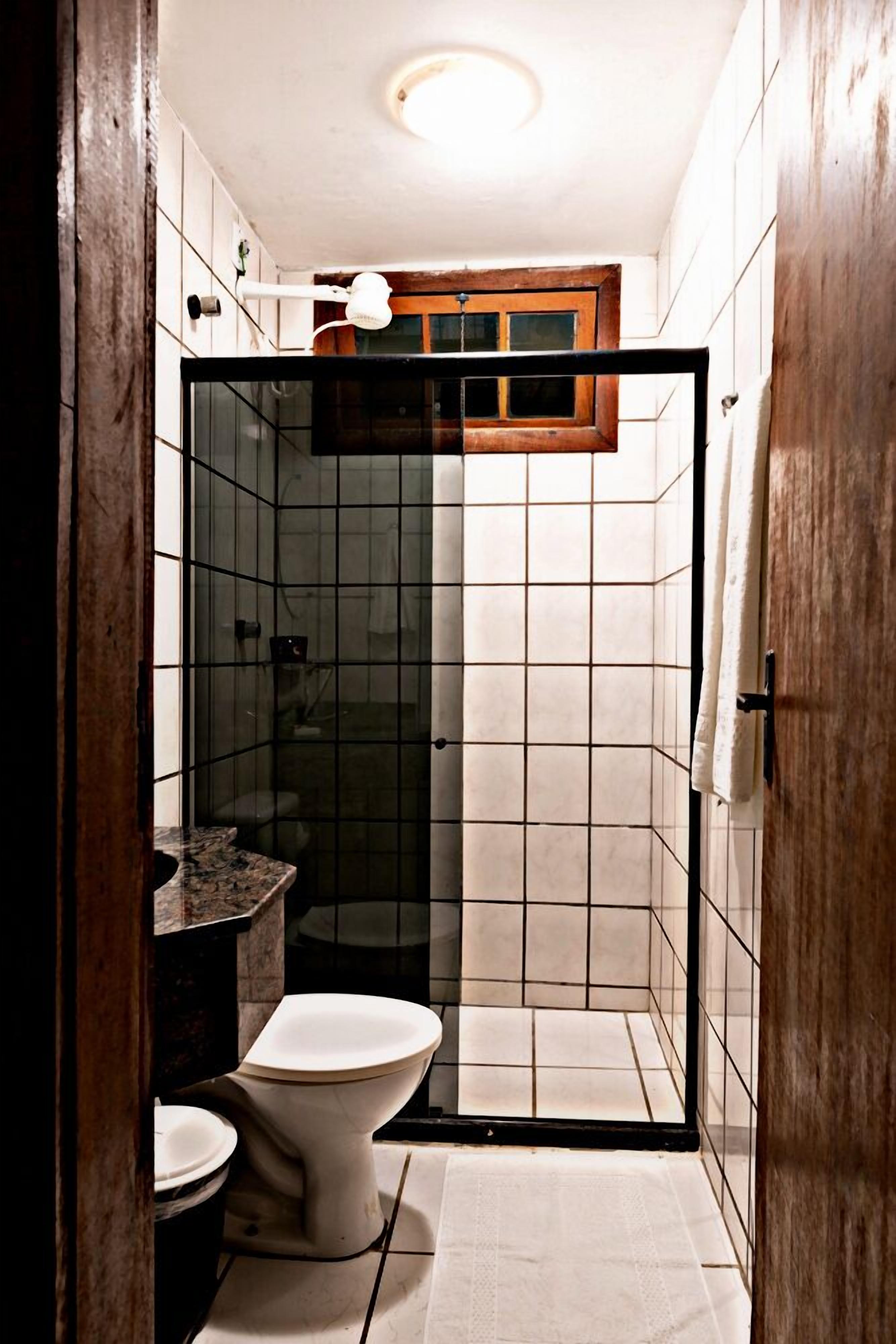 A compact bathroom with a glass-enclosed shower, a toilet, and a sink.