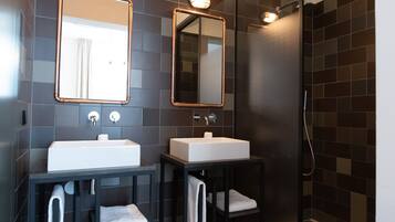 A modern bathroom with two sinks, a glass shower enclosure, and a large mirror.