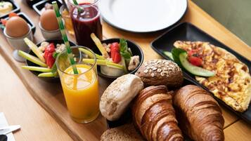 A breakfast tray with croissants, toast, a glass of orange juice, and a plate of scrambled eggs.