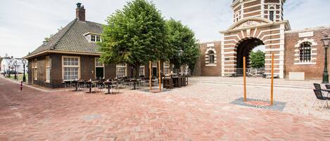 Un patio con piso de ladrillo, un edificio con cúpula y un árbol.