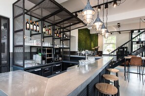Eine moderne Bar mit Theke, Hockstühlen und Regalen voller Flaschen und Gläsern.