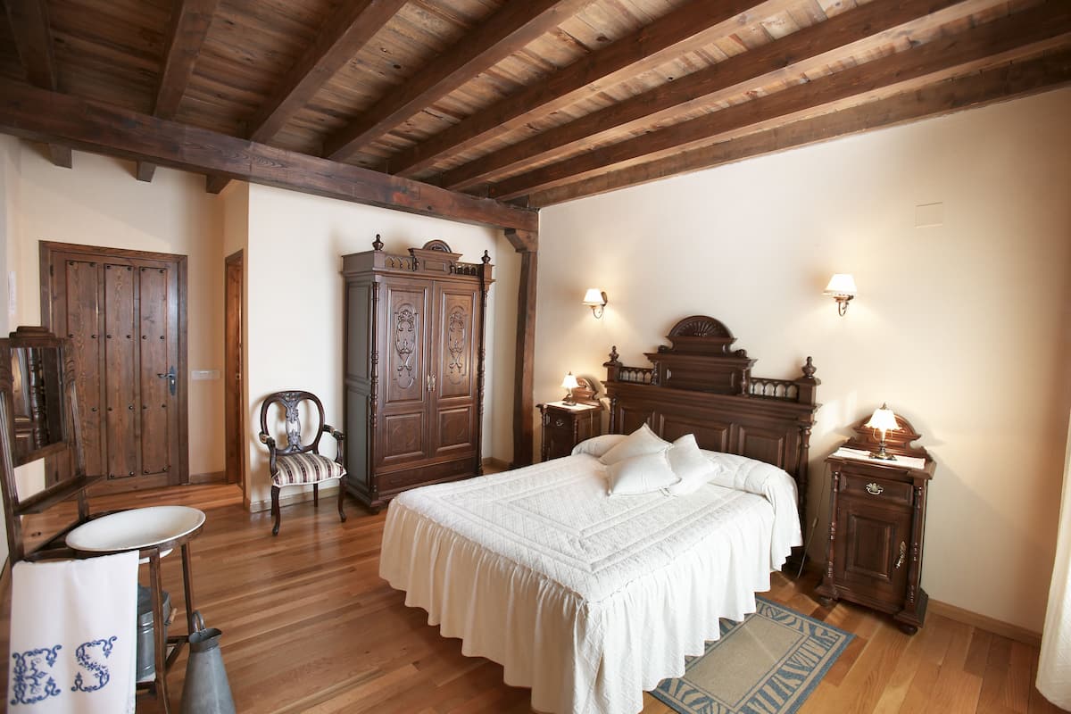 Ein Schlafzimmer mit einem hölzernen Bett, einem Schminktisch, einem Sessel und einem Nachttisch.