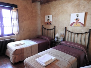 Una habitació amb dos llits, una finestra i obra d'art a les parets.