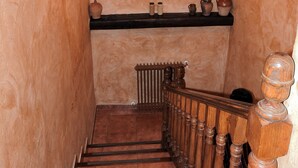 A wooden staircase with a black handrail and a rustic wall with a mounted animal skull and decorative items. - Casa Rural La Majada Palentina (Santibanez de la Pena)