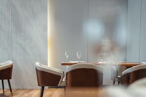 A modern dining area with a wooden table set for two, accompanied by a chair with a leather seat and wooden armrest. - Holiday Inn Ulaanbaatar by IHG (Ulaanbaatar)