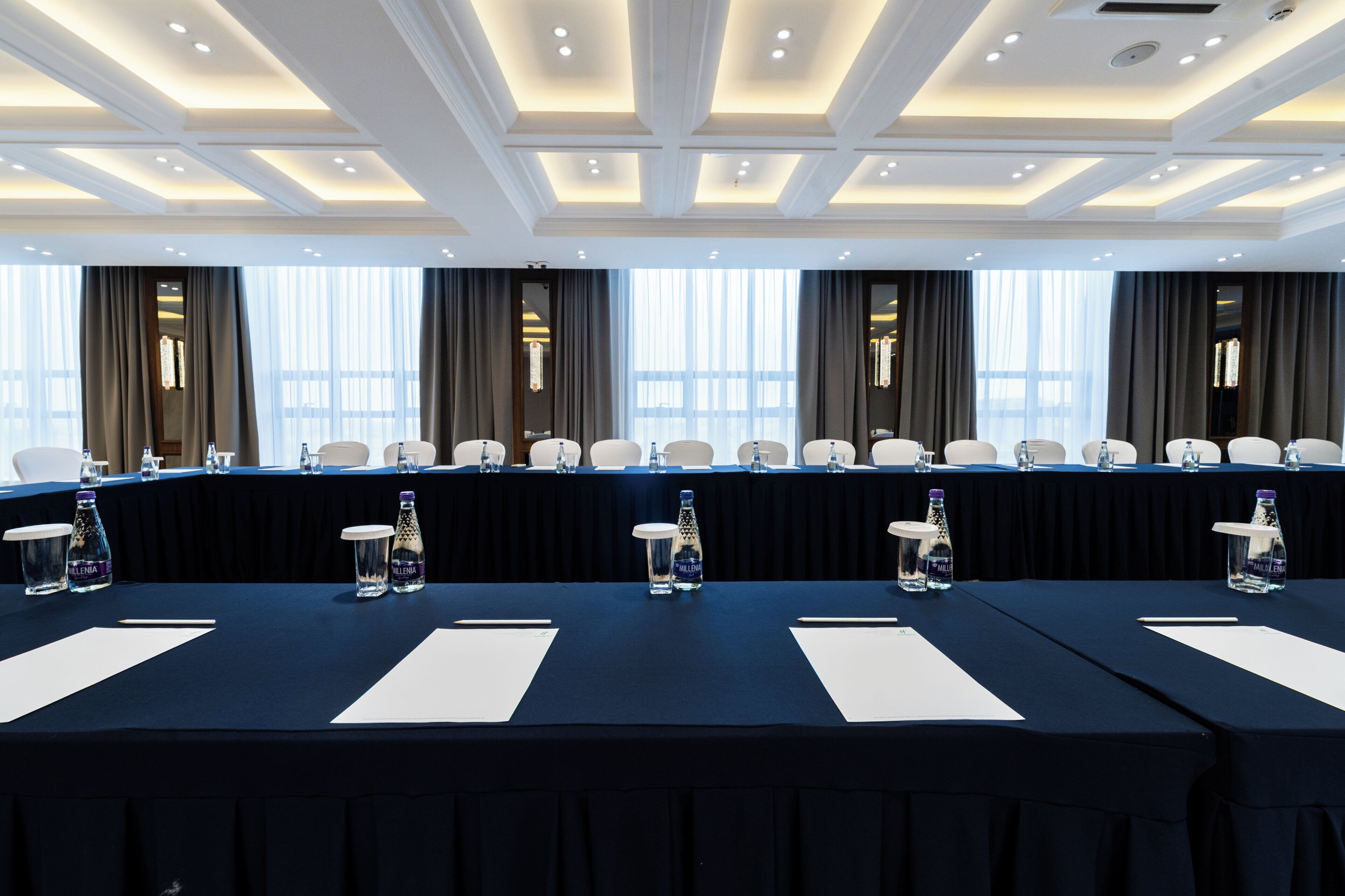 Una sala de conferencias con una mesa larga, sillas y botellas de agua.