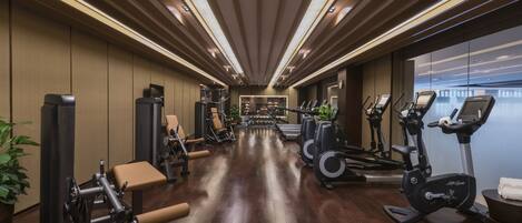 A gym with exercise equipment, wooden floors, and a view of the city.