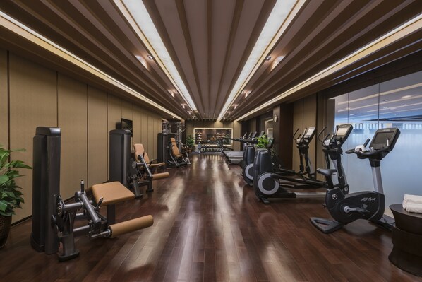 A gym with exercise equipment, wooden floors, and a view of the city. - Holiday Inn Ulaanbaatar by IHG (Ulaanbaatar)