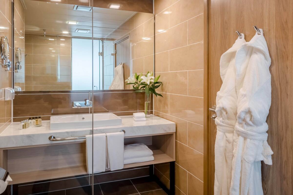 A modern bathroom with a glass shower enclosure, a marble sink, and a wooden vanity.