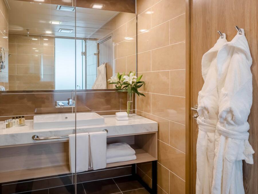 Ein modernes Badezimmer mit Duschkabine aus Glas, Marmorwaschbecken und Holzkommode.