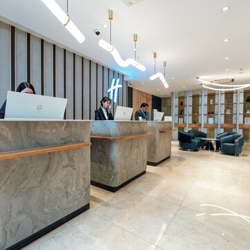A reception area with marble counters, modern lighting, and a seating area with sofas.