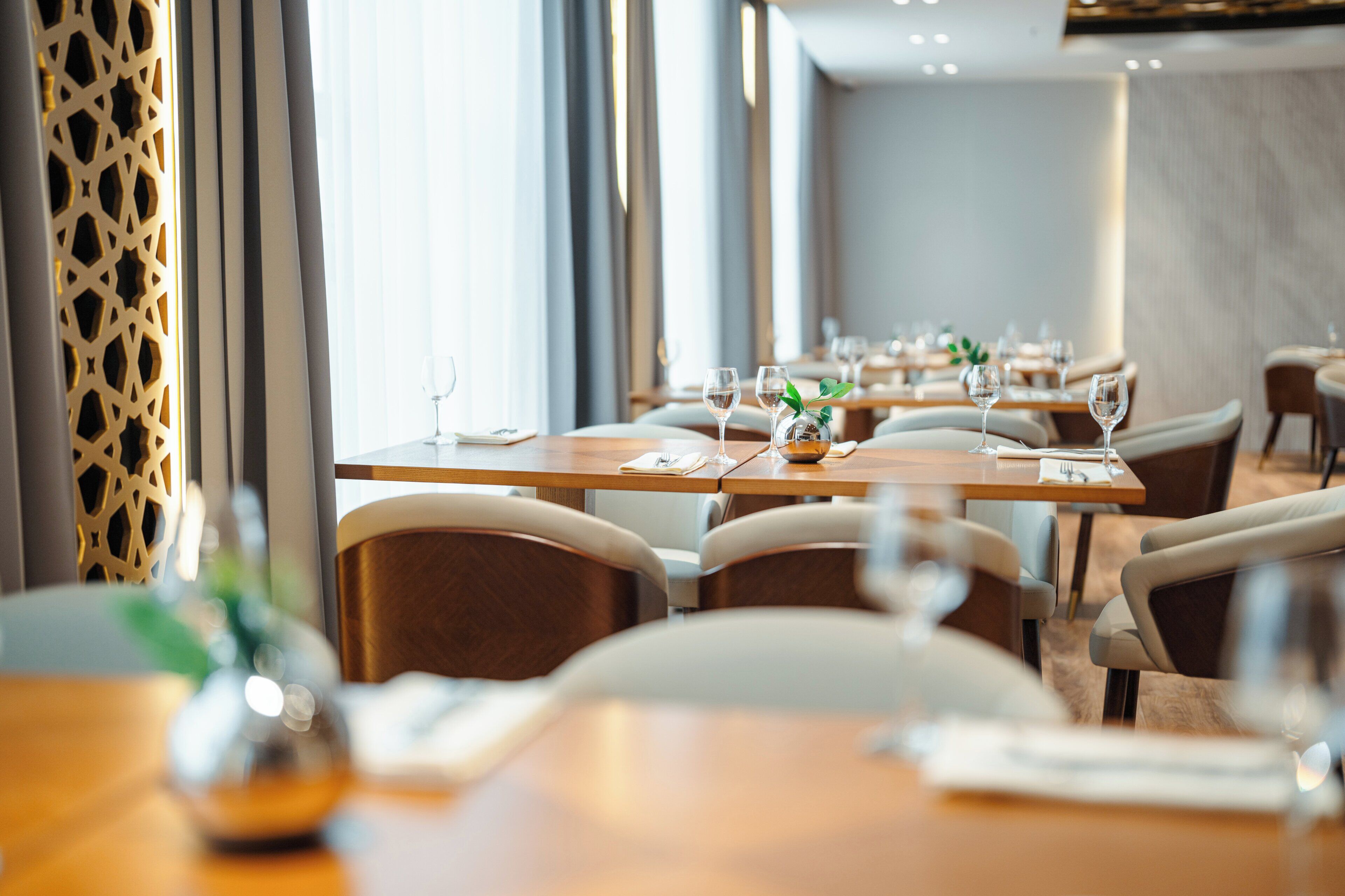Un restaurante con mesas dispuestas para comer, sillas y una pared decorativa.