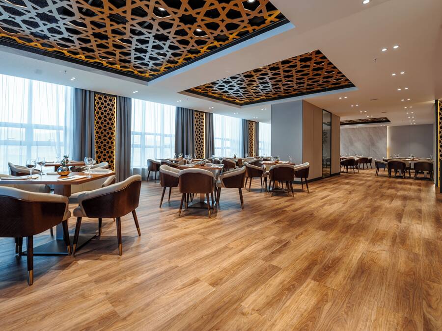 A modern dining area with wooden flooring, multiple tables, and chairs.