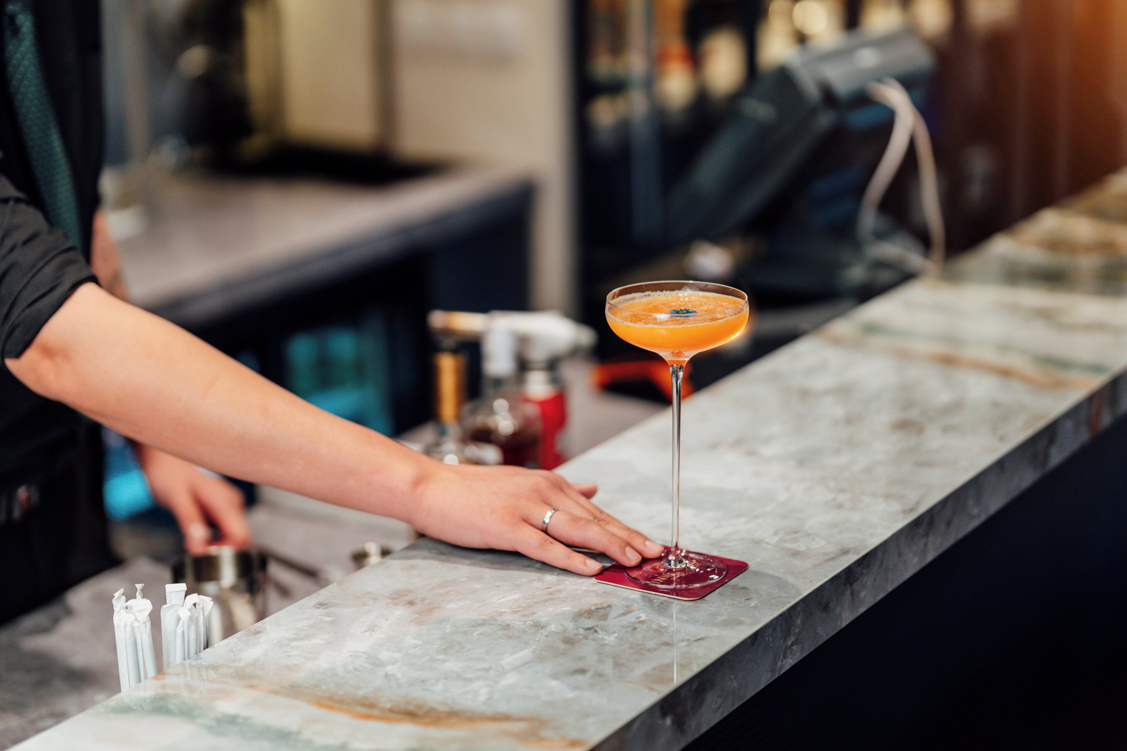 Un comptoir de bar avec un verre à martini contenant un cocktail.