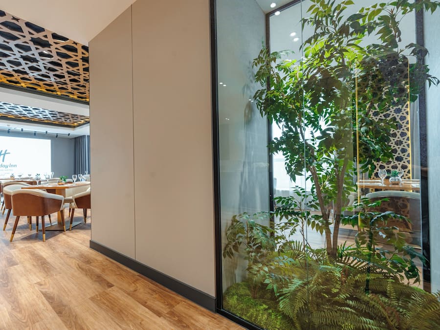 Eine moderne Hotelhalle mit Essbereich, Holzboden und einer großen Indoor-Pflanzenwand.