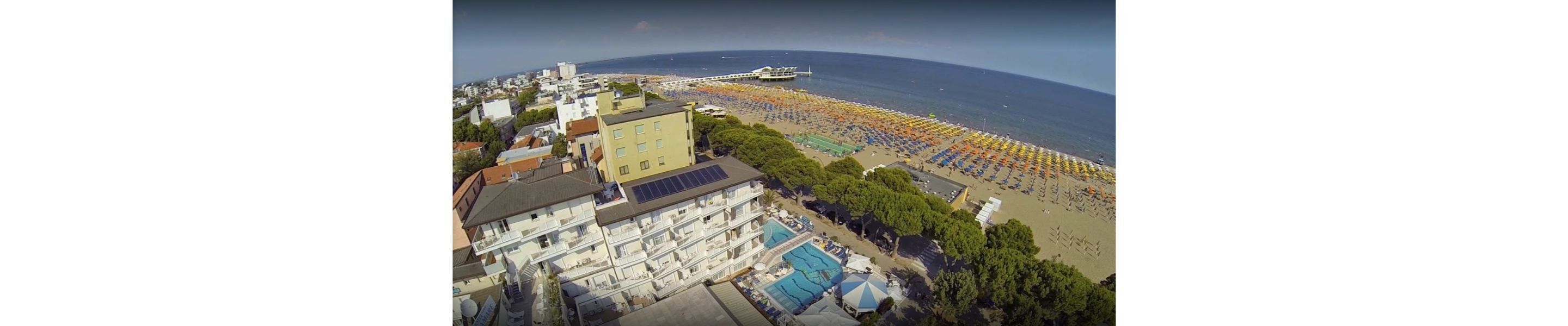 Vue aérienne d’une zone côtière avec une plage, une piscine et un immeuble à plusieurs étages.