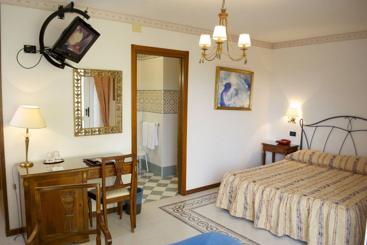 Une chambre d’hôtel équipée d’un bureau, d’une chaise, d’un lit et d’un miroir.