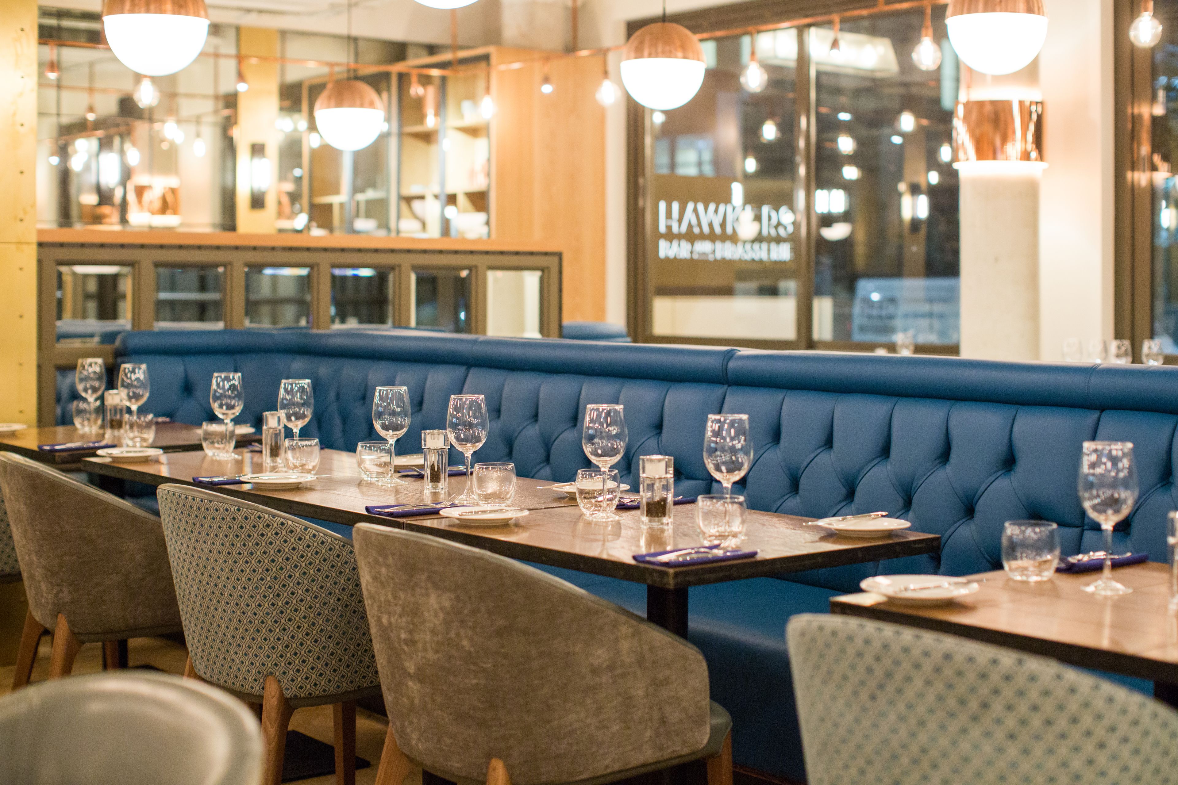 Un restaurante con asientos tapizados en azul, mesas de madera y sillas estampadas.