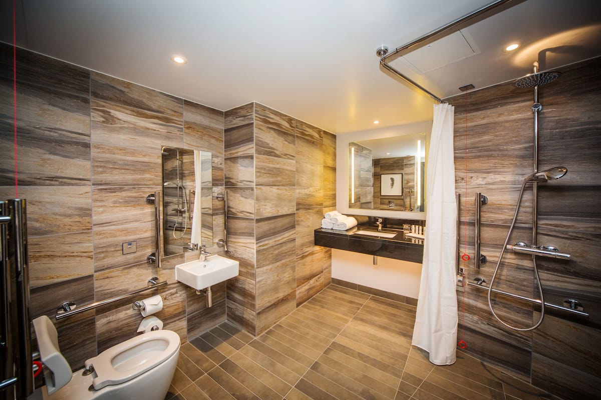 Un baño moderno con ducha, inodoro, lavabo y un espejo grande.