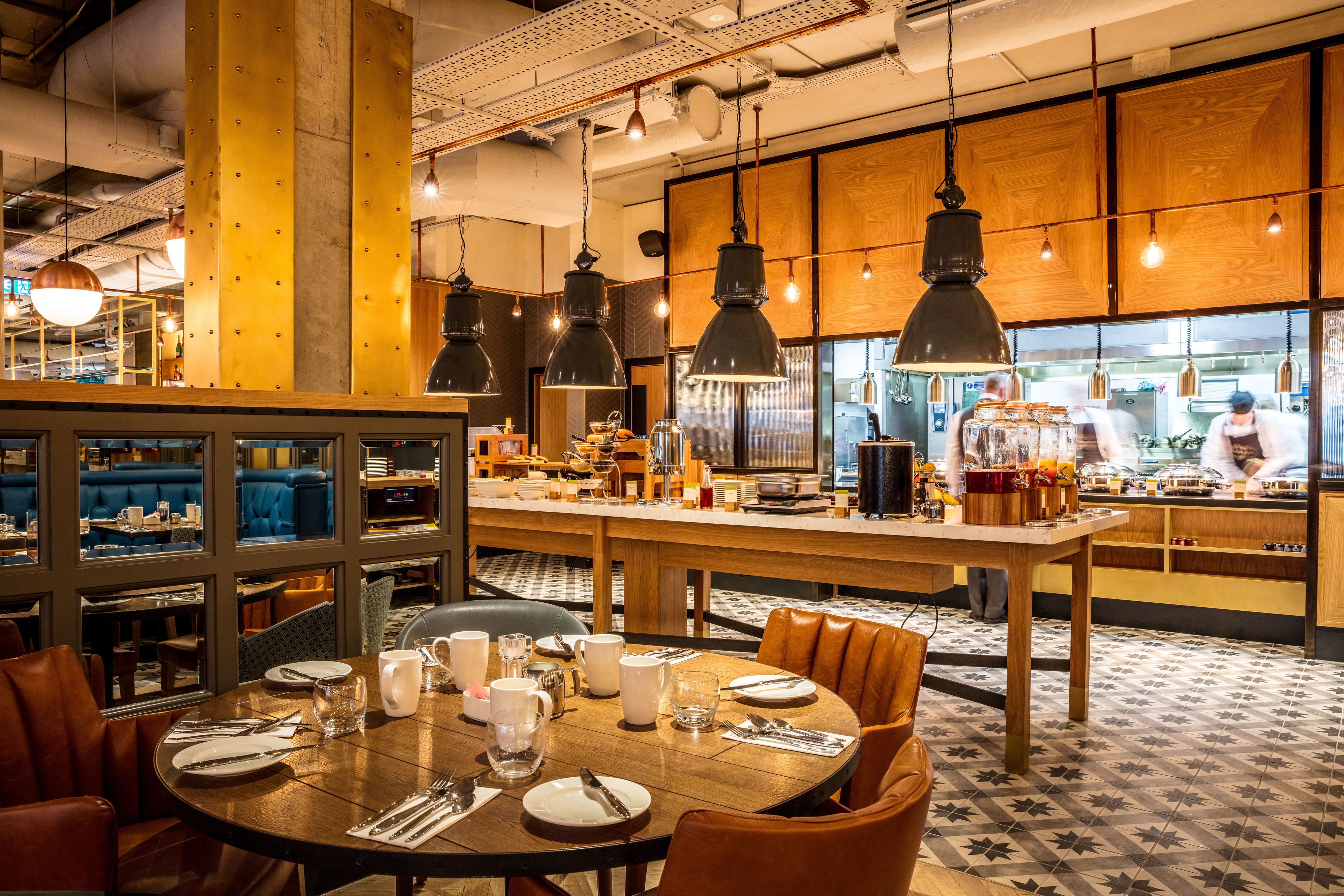 Un restaurante con comedor central, cabinas y cocina al fondo.