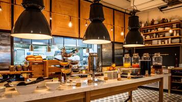 Un buffet proposant une variété de plats et de boissons, des meubles en bois et des lampes suspendues.