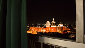 Vista nocturna de un paisaje urbano con edificios iluminados, incluyendo una iglesia destacada con dos cúpulas.