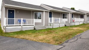 Une rangée de maisons mobiles de plain-pied, avec des balustrades blanches et des portes bleues.
