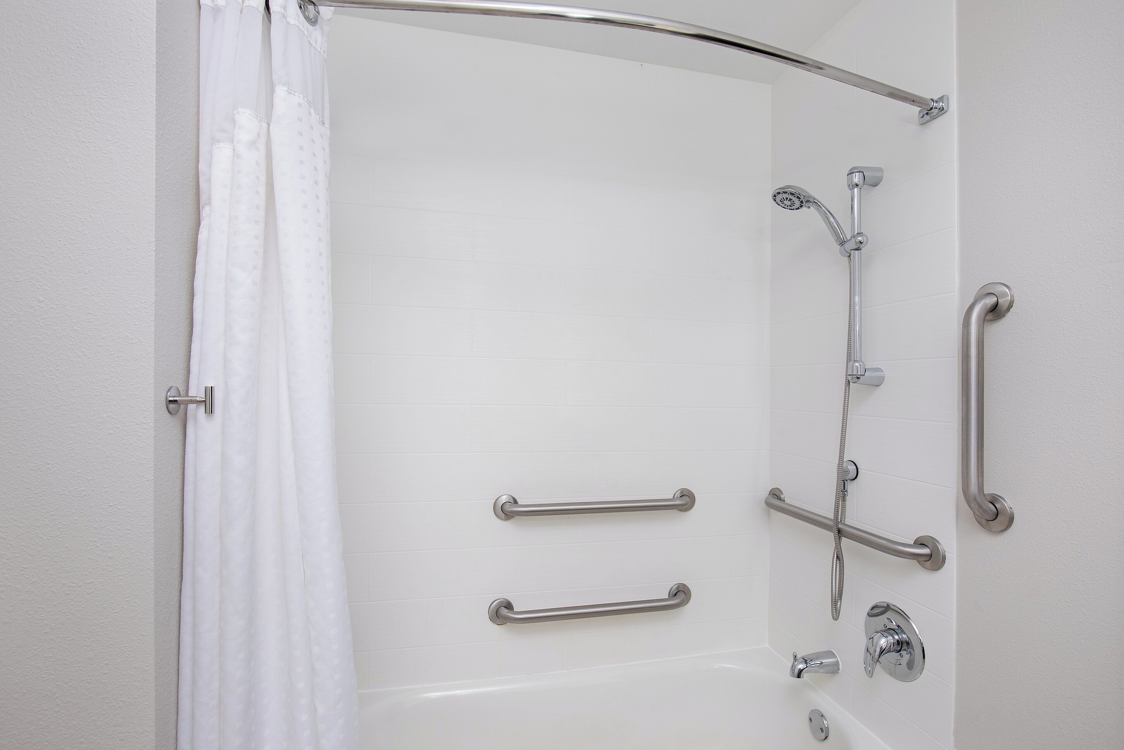 A modern bathroom with a walk-in shower, grab bars, and a handheld showerhead.