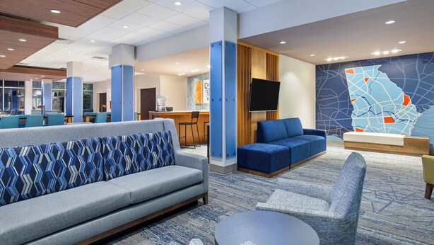 A modern hotel lobby with seating areas, a reception desk, and a large map on the wall. - Holiday Inn Express & Suites Carrollton West by IHG (Carrollton)