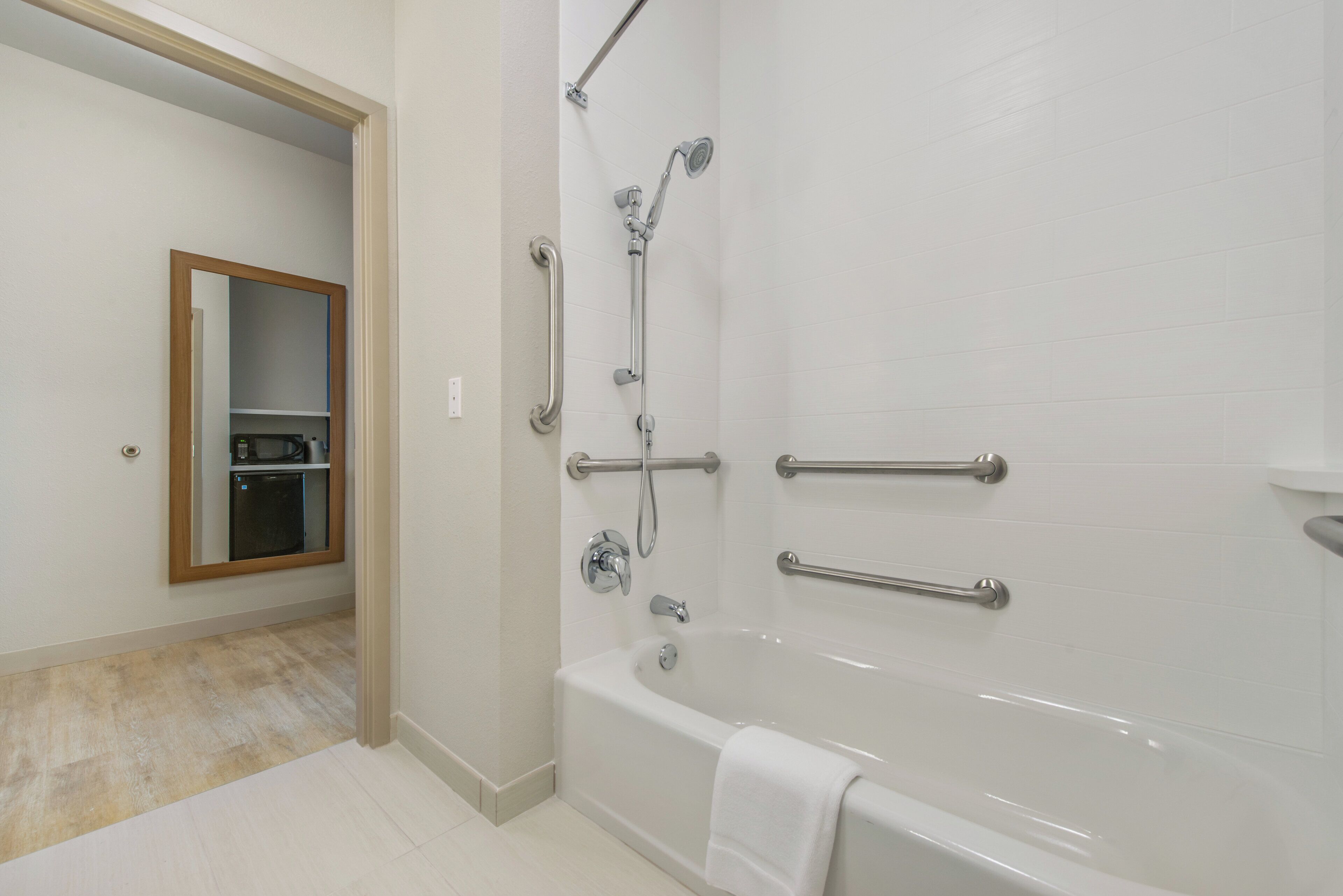 Un baño con bañera, ducha y barra de apoyo.