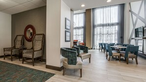 Eine Hotelhalle mit Sitzgelegenheiten, einer Rezeption und großen Fenstern.